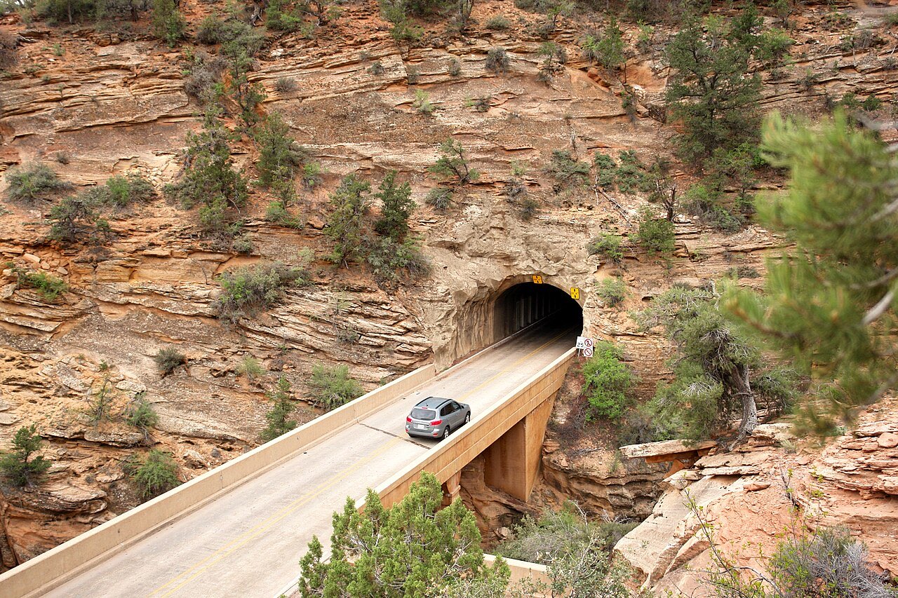 A car leaving the east portal of the Zion-Mount Carmel Tunnel on a bridge cut into red sandstone cliffs